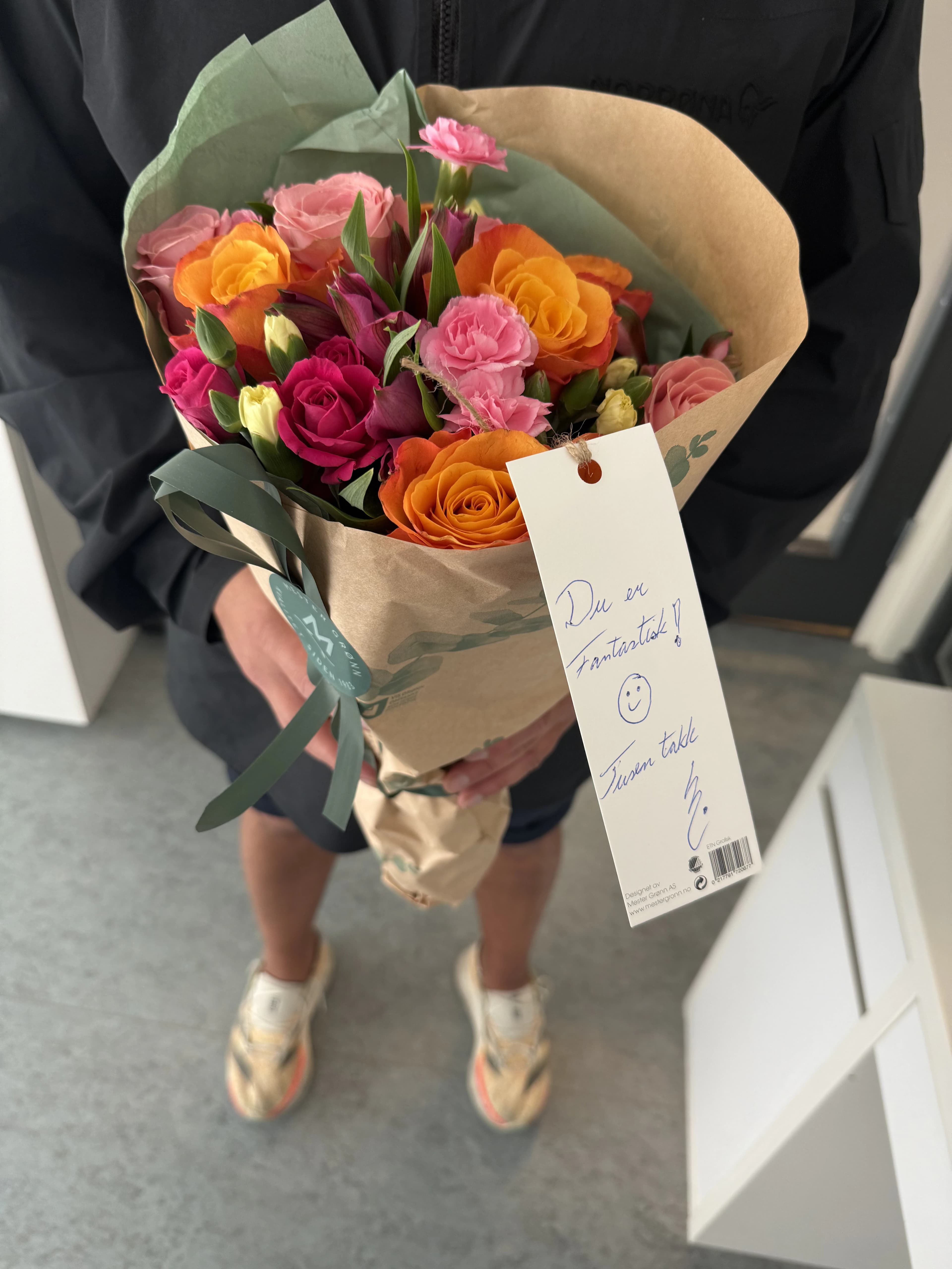 Fargerik blomsterbukett med et håndskrevet takkekort fra en kunde